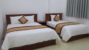 a bedroom with two beds with white sheets at Hoang Ngoc Hotel in Dĩ An +10 photos