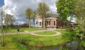 a large brick house with a walkway in front at Moushouk Bed and Breakfast in Oostwold
