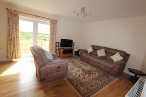 a living room with a couch and a chair at Glenside Cottage with Hot Tub in Solva