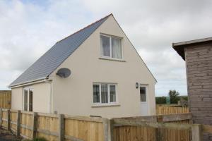 a white house with a wooden fence at Glenside Cottage with Hot Tub in Solva