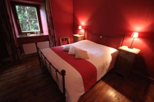 - une chambre avec un grand lit aux murs rouges dans l'établissement Comme à la Ferme, à Durbuy