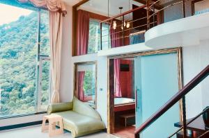 um quarto com uma cadeira verde e janelas grandes em Hi-Star View Hotel em Xizhi