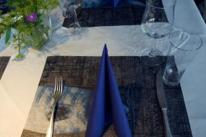 a table with a blue napkin and a fork and knife at Hotel Fresena in Baltrum