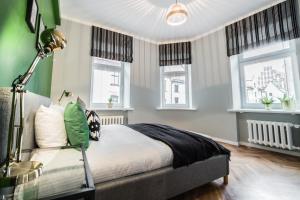 a bedroom with a bed and two windows at Greystone Suites & Apartments in Rīga