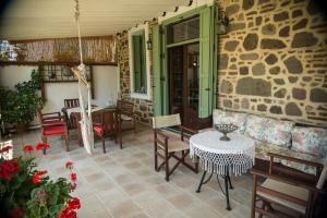 eine Terrasse mit einem Tisch, Stühlen und einer Steinmauer in der Unterkunft Archontiko Petras 1821 in Petra