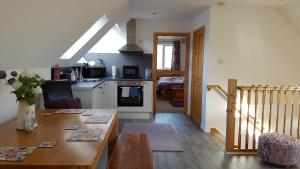 a kitchen and living room with a table and a kitchen at An Cois Na H-Aibhne in Skeabost