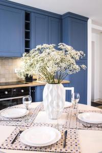 a blue kitchen with a table with plates and a vase of flowers at Marine Preila in Preila