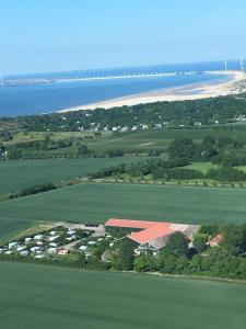 een luchtzicht op een veld met een gebouw en een strand bij Rustenpolder kamperen en logeren in Vrouwenpolder