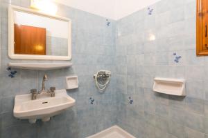 a blue tiled bathroom with a sink and a mirror at Nikos Apartments 1 in Kavos