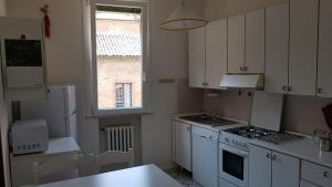 a small kitchen with white cabinets and a window at Una Notte al Museo in Ferrara