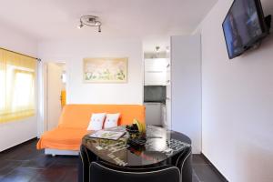 un soggiorno con divano arancione e tavolo di Studio Apartment Maslina a Gornji Karin (Carino)