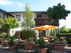 a patio with tables and chairs and an umbrella at Restaurant Landgasthof Zum Wiesengrund in Newel