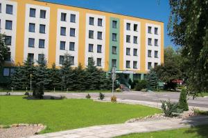 克拉科夫的住宿－克拉庫斯酒店，街道上一座黄色和白色的大建筑