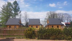 three houses with black roofs behind a wooden fence at Eko domki MaMastra Szaflary in Szaflary