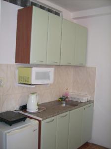 a kitchen with green cabinets and a sink and a microwave at Hotel Pasians in Pomorie