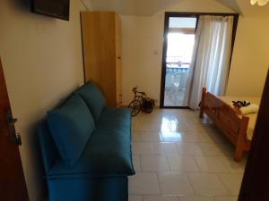 a living room with a blue couch and a window at Christakos Apartments in Nea Vrasna