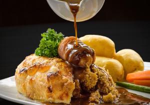a plate of food with a sauce being poured on a chicken at Atholl Hotel in Aberdeen