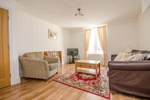 a living room with a couch and chairs and a table at Cosy Llandudno Apartments in Llandudno