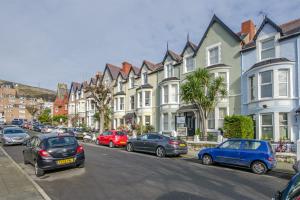 a row of houses on a city street with cars parked at Cosy Llandudno Apartments in Llandudno