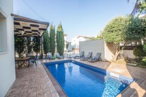 una piscina en un patio trasero con sillas y mesa en Katerina Luxury Villas, en Protaras