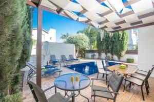 un patio con mesa, sillas y piscina en Katerina Luxury Villas, en Protaras