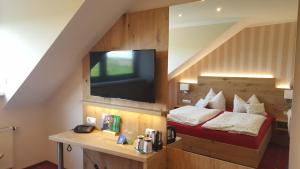 a room with a bed and a tv on the wall at Landhotel BurgenBlick Garni & Tagungshotel in Erfurt