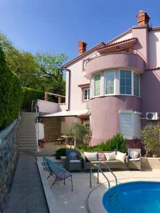 a pink house with a pool in front of it at Apartments Melanie in Opatija
