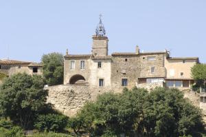 um antigo edifício de pedra numa colina com árvores em Hostellerie Le Roy Soleil em Ménerbes