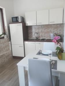 a kitchen with white cabinets and a table with wine glasses at Apartmani Gojko in Sali