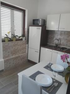 una cocina con armarios blancos y una mesa con 2 platos en Apartmani Gojko, en Sali