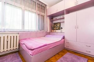 a pink bedroom with a bed and a window at Апартамент Бриз in Burgas City