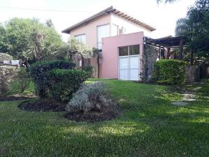 une maison rose avec une pelouse devant elle dans l'établissement Paraiso Colon, à Colón