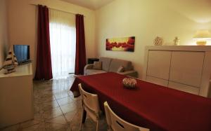 un soggiorno con tavolo rosso e un soggiorno con divano di La Baia Apartments by My Home Apulia a Torre Lapillo