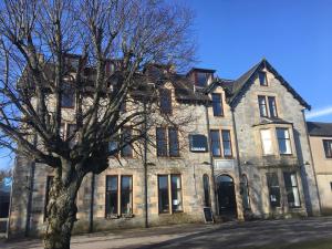 an old stone building with a tree in front of it at Hotel Square in Tomintoul