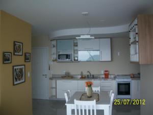 a kitchen with white cabinets and a table and chairs at Angra Super Luxo in Mangaratiba