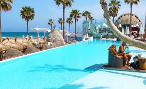 two women sitting next to a swimming pool at a resort at Apartments Valencia, Cabañal in Valencia