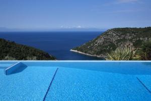 a blue swimming pool with a view of the ocean at Elies Houses in Agnontas