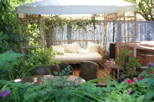 einen Garten mit einer weißen Couch in einem Pavillon in der Unterkunft Gan HaPaamonim in Giv‘ath Binyāmīn