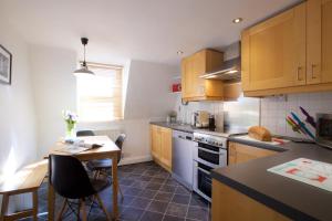 Una cocina con gabinetes de madera y una mesa con sillas. en Georgian House - Fantastic Central Apartment with Fabulous Views, en Bath