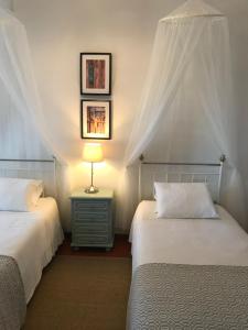 a bedroom with two beds and a lamp on a night stand at Herdade D. Pedro in Terena