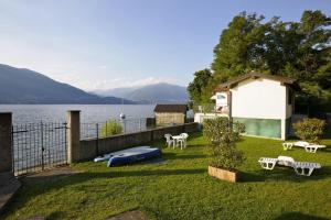 einen Hinterhof mit einem See und einem Haus und Bänken in der Unterkunft Casa al Lago Trentuno B in Zenna