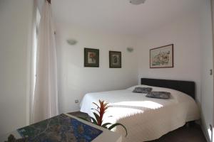 Dormitorio blanco con cama y mesa en Aurora Apartments, en Šibenik