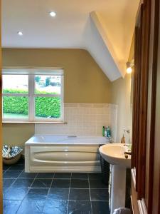 baño con bañera, lavabo y ventana en The-Gables, en Donegal