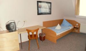 a small bedroom with a bed and a desk with a small television at Hotel Andernacher Hof in Andernach