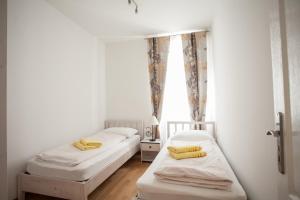 Apartment Bose في سبليت: سريرين في غرفة بجدران بيضاء ووسائد صفراء