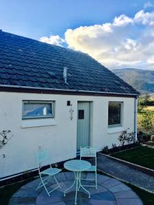 two chairs and a table in front of a house at Cosy Cottage in Glencoe