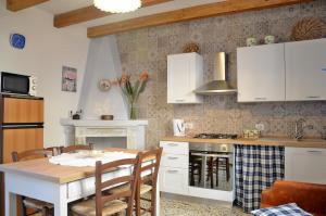 una cocina con armarios blancos y una mesa con sillas. en Guest House Sa Succargia en Baunei