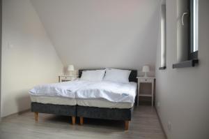1 dormitorio con 1 cama con sábanas y almohadas blancas en Pueblo Apartamenty en Stegna