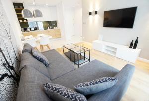uma sala de estar com um sofá e uma televisão em CHILLIapartamenty Bliżej Morza KORAL em Kolobrzeg