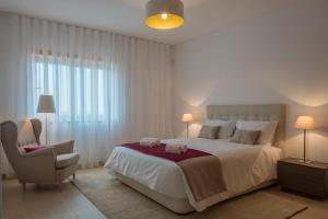 a bedroom with a large bed and a chair at Marvellous Villa in Óbidos